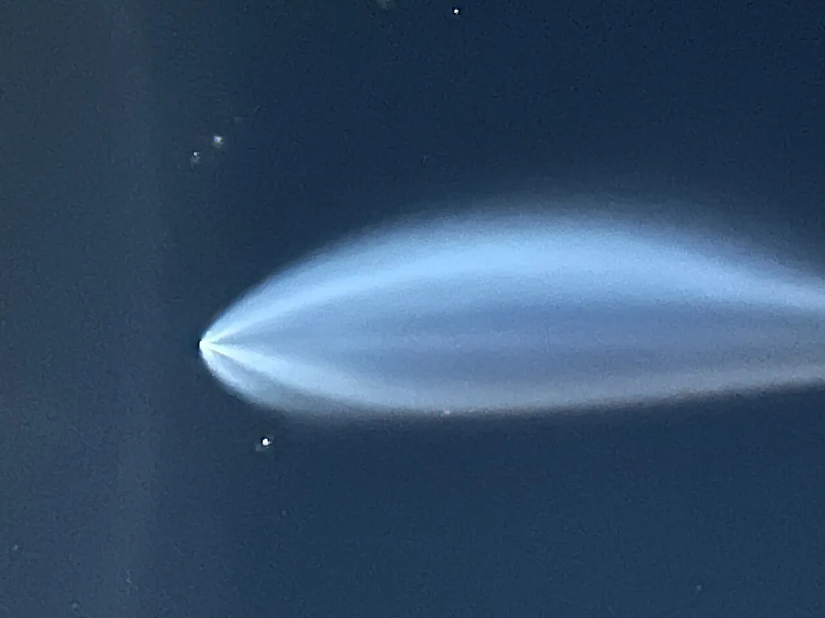 Glowing blue rocket exhaust plume in a dark sky