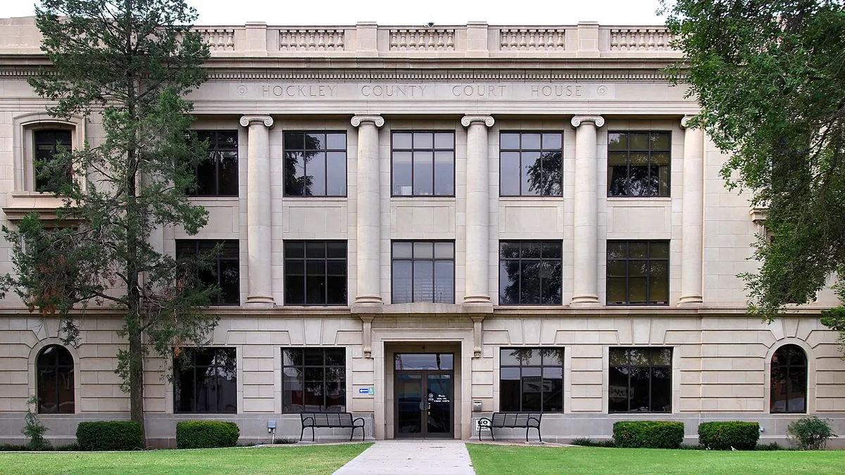 A three-story pale stone courthouse with tall columns and the words Hockley County Court House carved across the top